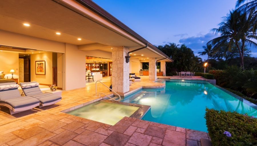 A well-lit, open-air home with a backyard pool and a tiki torch.