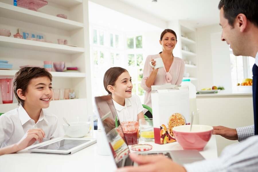 A family having breakfast together while using smart devices.