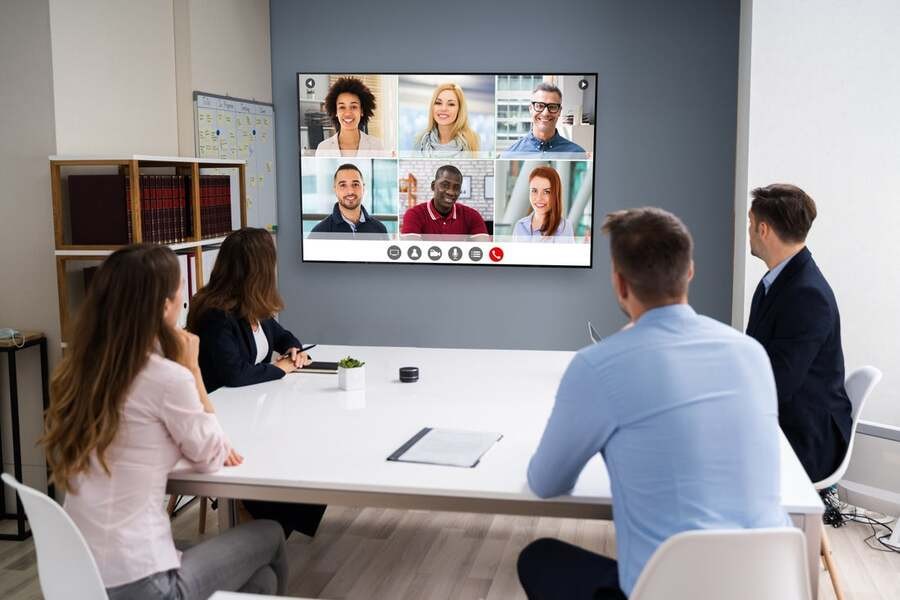 A group of people hold a video meeting with hybrid coworkers.