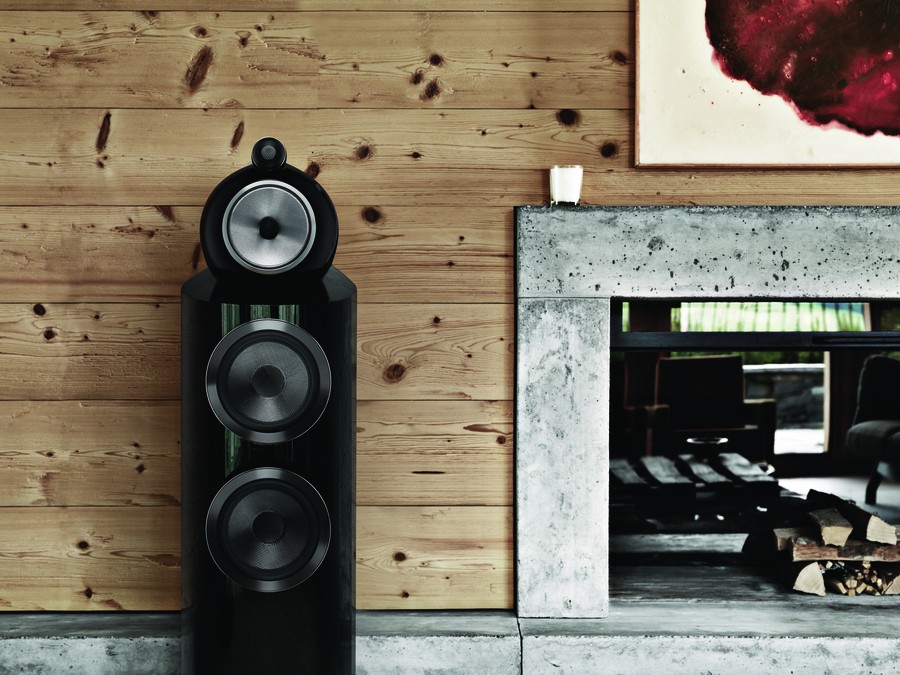 Close-up of a black Bowers & Wilkins 802D4 Speaker placed next to a fireplace. 